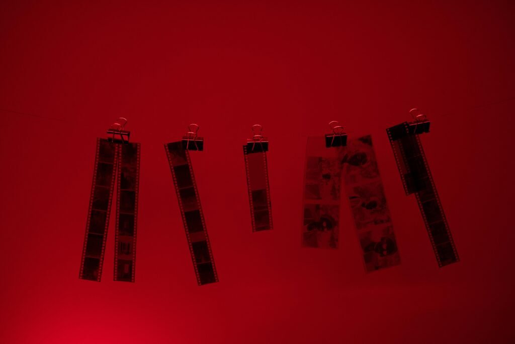 pexels-photo-10273414-10273414 Hanging film strips illuminated by red darkroom light during development.