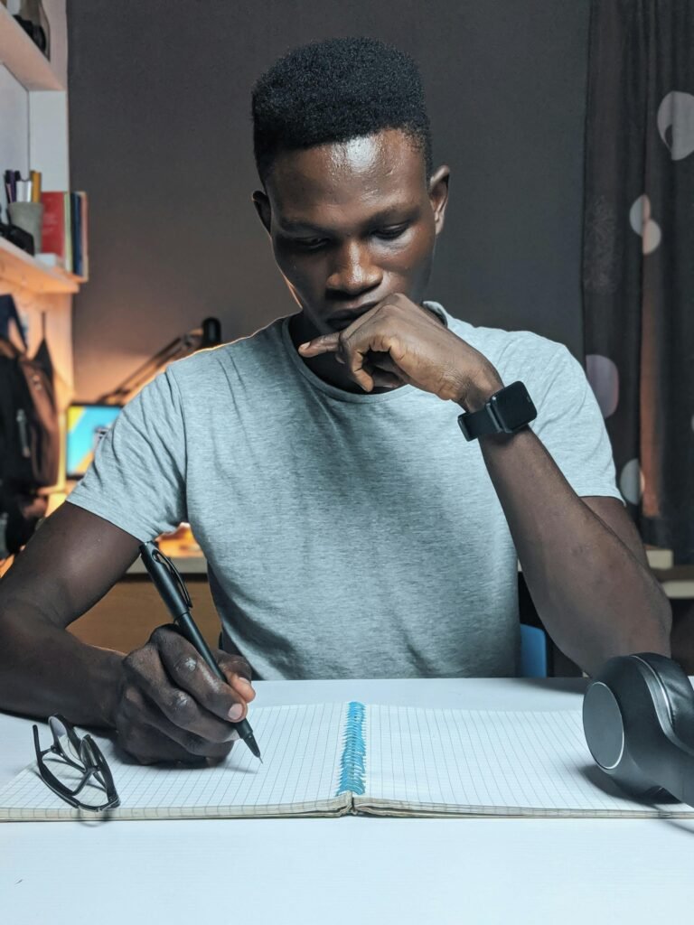 pexels-photo-2989397-2989397 Man deeply focused while writing in a notebook on a desk with a thoughtful expression.